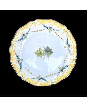 Majolica plate with brim decorated with festoons and rocaille motifs and vine leaf in the cavetto.Ferniani manufacture.Faenza.     