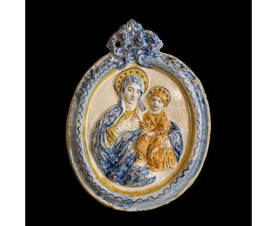 Formella devozionale Madonna con bambino di forma ovale con motivo rocaille superiore.Faenza o Imola.