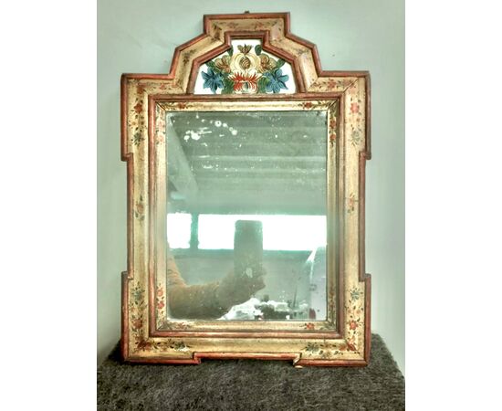Specchiera in legno laccato con dipinto su vetro a soggetto floreale.Italia settentrionale.