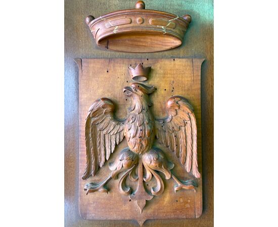 Pannello in legno di noce  con applicato stemma nobiliare con  figura di aquila e corona in altorilievo.