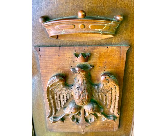 Pannello in legno di noce  con applicato stemma nobiliare con  figura di aquila e corona in altorilievo.
