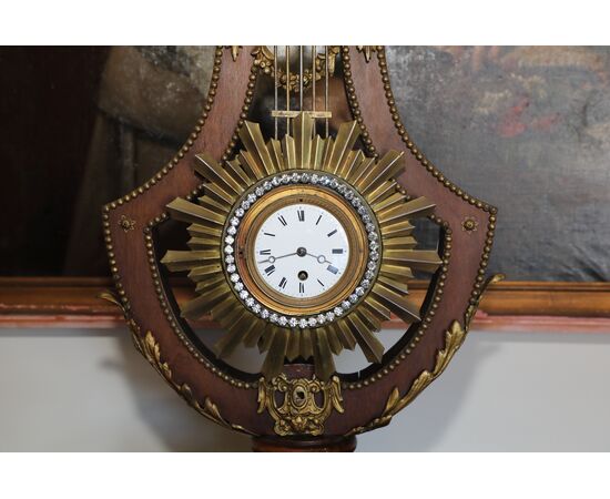 Orologio a pendolo  da appoggio in noce  a forma di lira con teste di aquila in legno dorato in stile impero