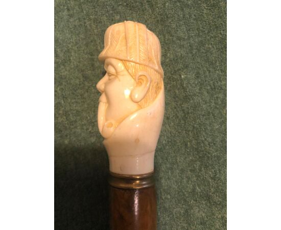 Bastone con pomolo in osso raffigurante figura maschile con cappello e pipa. 