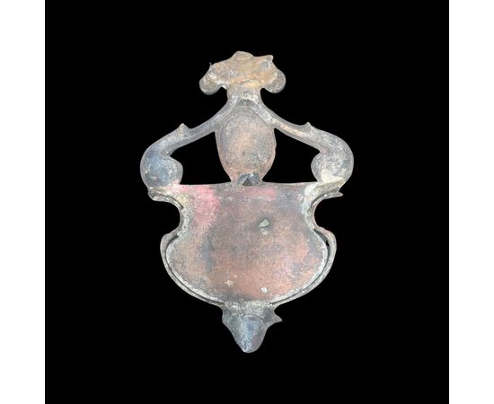 Acquasantiera in bronzo con vaschetta a bordo estroflesso,prese a ricciolo,putto e simbolo berardiniano.