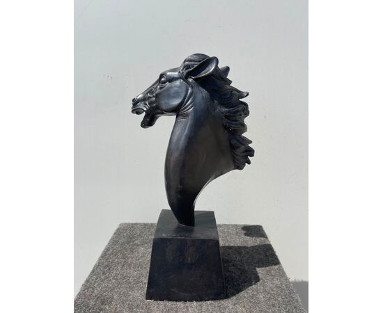 Scultura in bronzo con base raffigurante testa di cavallo.