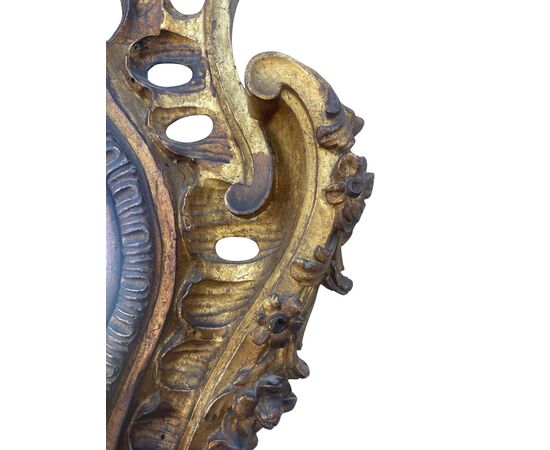 Specchiera in legno intagliato e parzialmente dorato con traforature, incisa a motivi rocaille e vegetali.
