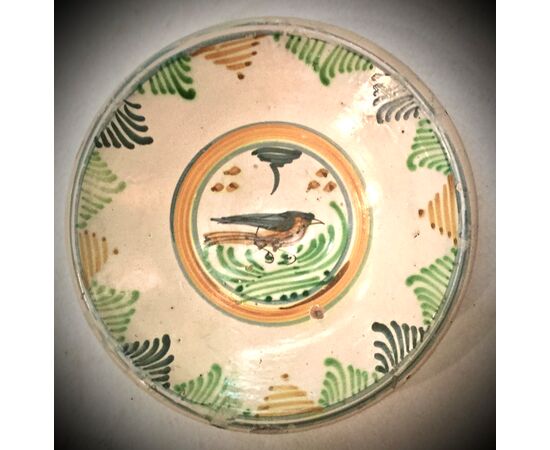 Majolica plate with stylized plant motifs on the brim and a bird in the umbo.Manifattura di Montelupo.     
