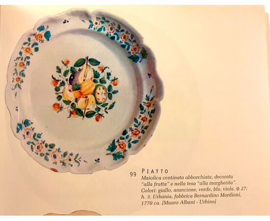 Piatto in maiolica con decori floreali sulla tesa e motivo alla ‘frutta barocca’ nel cavetto.Manifattura di Bernardino Mordioni.Urbania.