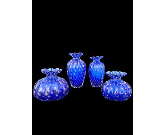 Serie di tre vasetti in vetro pesante blu a corpo costolato e bocca espansa con inclusione di bolle e foglia oro.Manifattura Barovier.Murano.