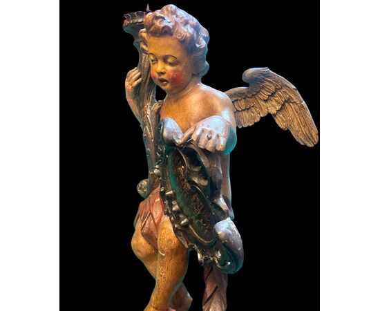 Scultura in legno policromo raffigurante un angelo con cornucopia e scudo rocaille con iscrizione.Paesi Bassi.