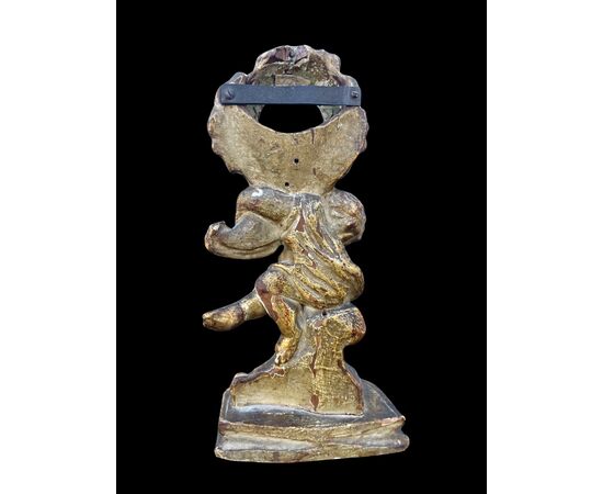 Porta orologio in legno scolpito e foglia oro raffigurante un fanciullo con elementi rocaille.