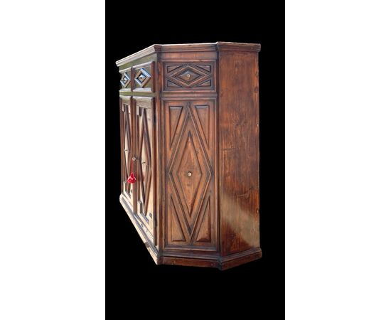 Credenza a sezione esagonale con due sportelli in legno di castagno e motivi geometrici.