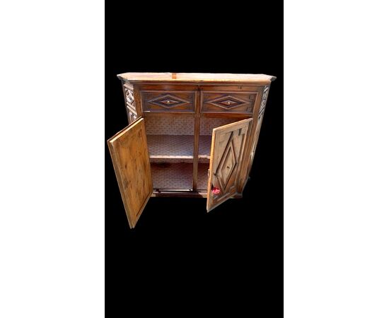 Credenza a sezione esagonale con due sportelli in legno di castagno e motivi geometrici.