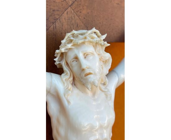 Cristo in avorio su cornice in legno intagliato.