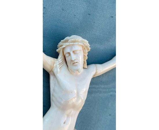 Cristo in avorio con cornice in legno sagomato e argentato.