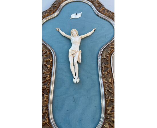 Cristo in avorio con cornice in legno sagomato e argentato.