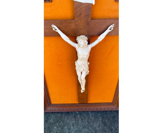 Cristo in avorio su cornice in legno intagliato.