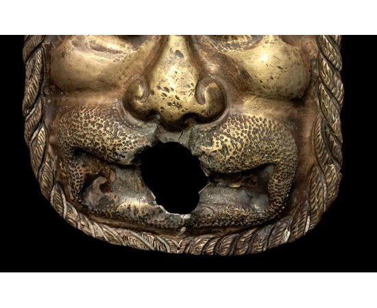 Affascinante mascherone in metallo dorato, probabilmente bocca di fontana