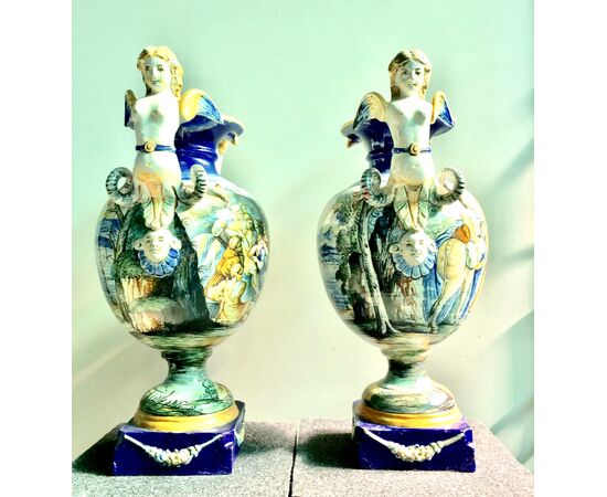 Pair of majolica vases with side sockets in the shape of a harpy and historiated decoration.Author: Tito Magrini.Pesaro.     