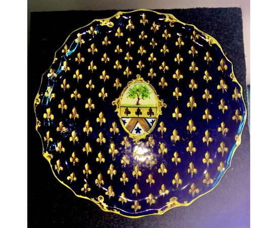 Piatto alzata in maiolica decorato con motivo a giglio mediceo e stemma nobiliare al centro.Manifattura di Angelo Minghetti,Bologna.