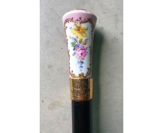 Stick with porcelain knob with floral decoration and gallant scene. Ebony case. France.     