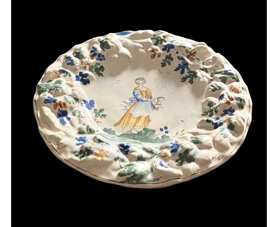 Piatto in maiolica con tesa a fiori in rilievo  e decoro con figura femminile con versatoio. Baldassarre Caravaggio.Pavia.