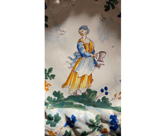 Piatto in maiolica con tesa a fiori in rilievo  e decoro con figura femminile con versatoio. Baldassarre Caravaggio.Pavia.