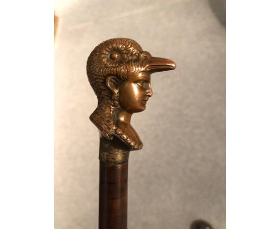 Defense stick with solid bronze pommel depicting a female head with a bird-shaped helmet.     