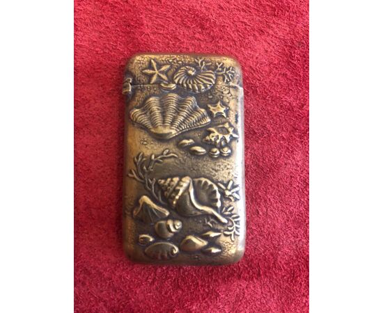 Brass matchbox depicting seashells and marine fauna and flora.     