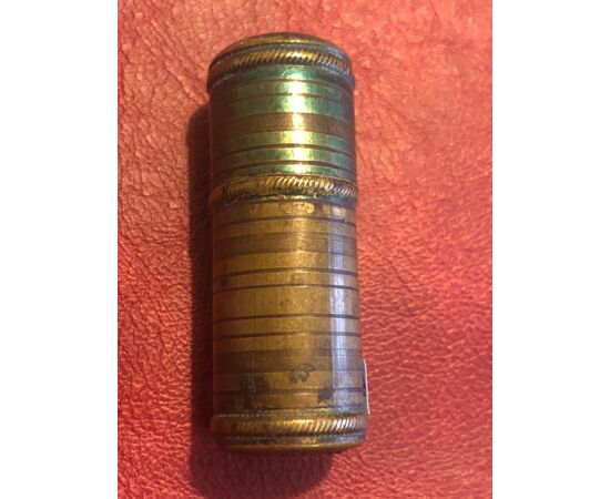 Cylindrical brass matchbox with geometric decorations.     