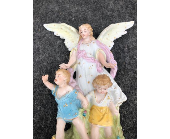 Acquasantiera in porcellana bisquit con figura di Angelo ad ali spiegate che protegge due bambini.Francia.