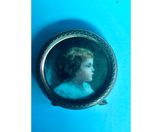 Miniature on ivory depicting a boy with a brass frame.     