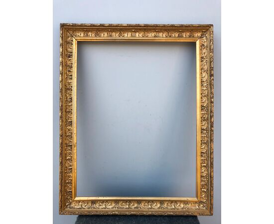 Carved and gilded wooden frame with stylized plant motifs.     