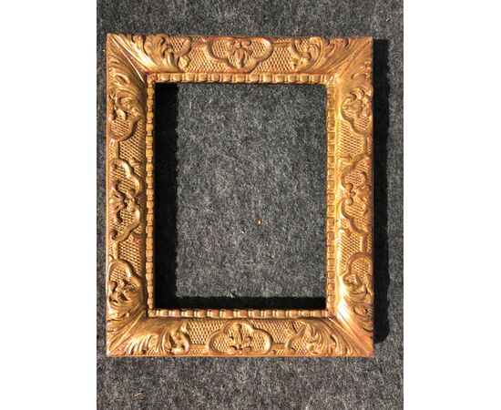 Carved and gilded wooden frame with stylized plant motifs and rocaille and knurling.     