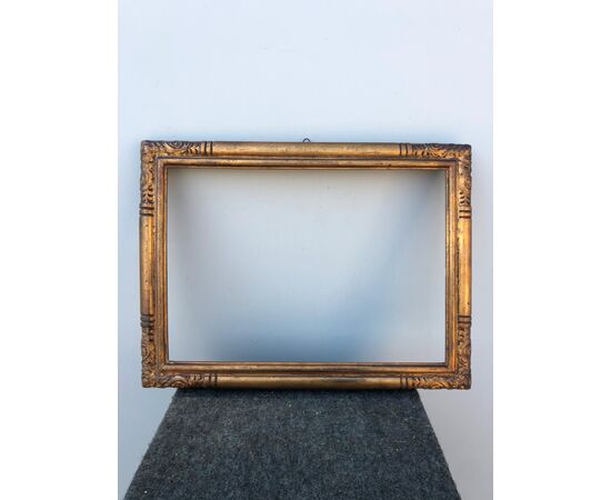 Carved and gilded wooden frame with stylized plant motifs.     