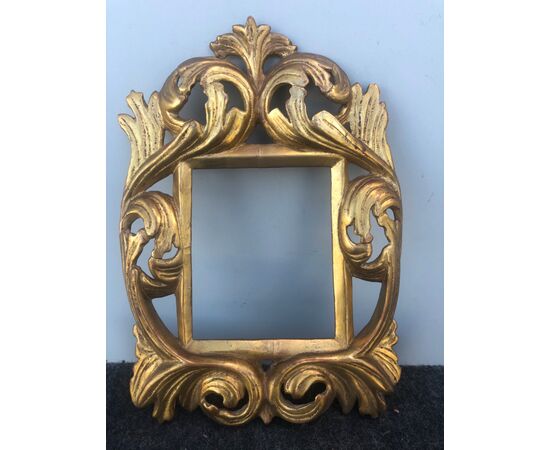 Carved and gilded wooden foil frame with stylized plant motifs.     
