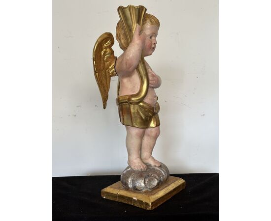 Angelo reggicornucopia in legno intagliato dorato. XVIII secolo.