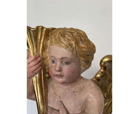 Angelo reggicornucopia in legno intagliato dorato. XVIII secolo.