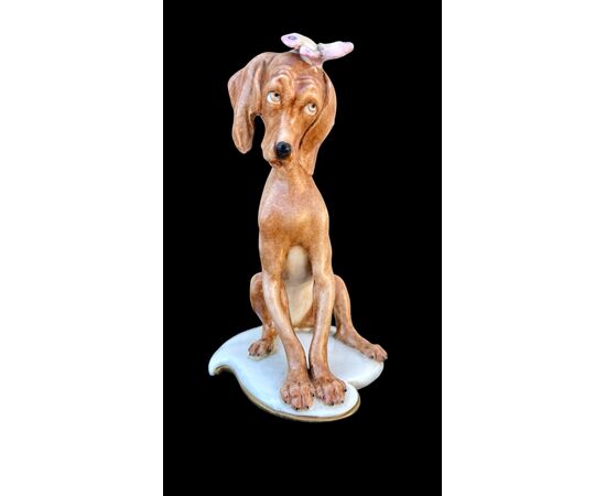 Figura di cane in porcellana con farfalla. Manifattura Cappe’.