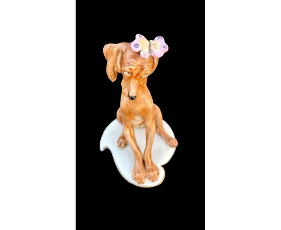 Figura di cane in porcellana con farfalla. Manifattura Cappe’.