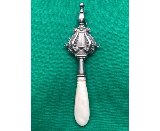 Baby rattle in silver with stylized plant motifs and lyre. Mother of pearl handle.     
