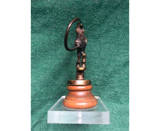 Bronze statue mounted on a wooden base depicting a devil making raspberry.     