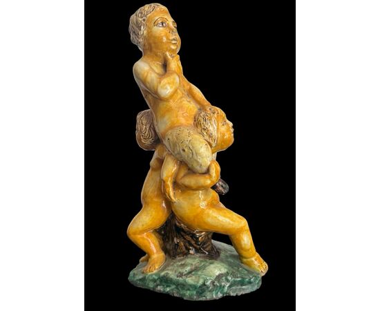 Scultura in maiolica policroma con due fanciulli che reggono un fauno.Nicola Giustiniani.Napoli.