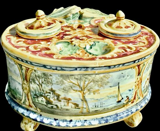 Calamaio in maiolica a 4 piedi con presa a forma di foglia e decoro con medaglioni con paesaggi e personaggi.Manifattura Minghetti.Bologna.