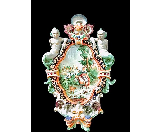 Two-light majolica candlestick wall lamp with grotesque figures on the sides and a central historiated medallion. Battaglia manufacture. Naples.