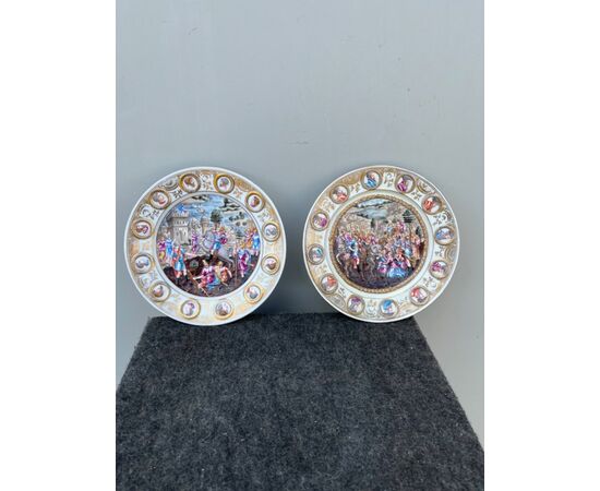 Coppia di piatti in porcellana a ‘bassorilievo istoriato’ policromo con scene di battaglia e medaglioni con profili maschili.Ginori.