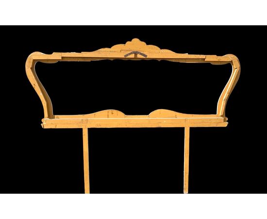 Testiera letto in legno scolpito con motivi rocaille color crema e oro.