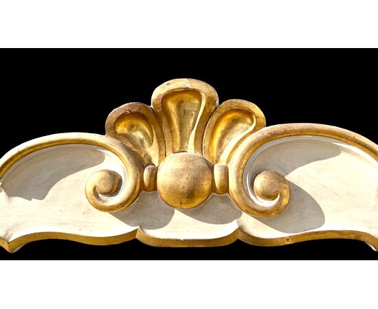 Testiera letto in legno scolpito con motivi rocaille color crema e oro.