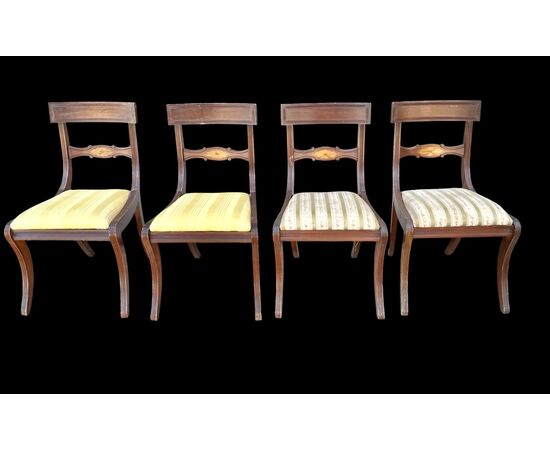 Four walnut chairs with geometric pattern decoration.