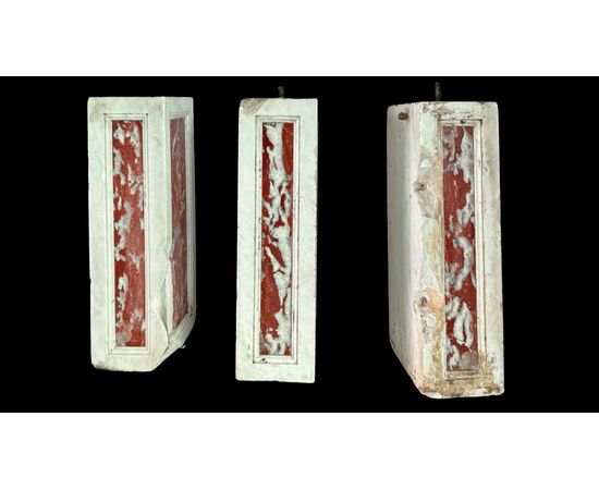 Three architectural elements in marble with a white frame and a variegated red central section.